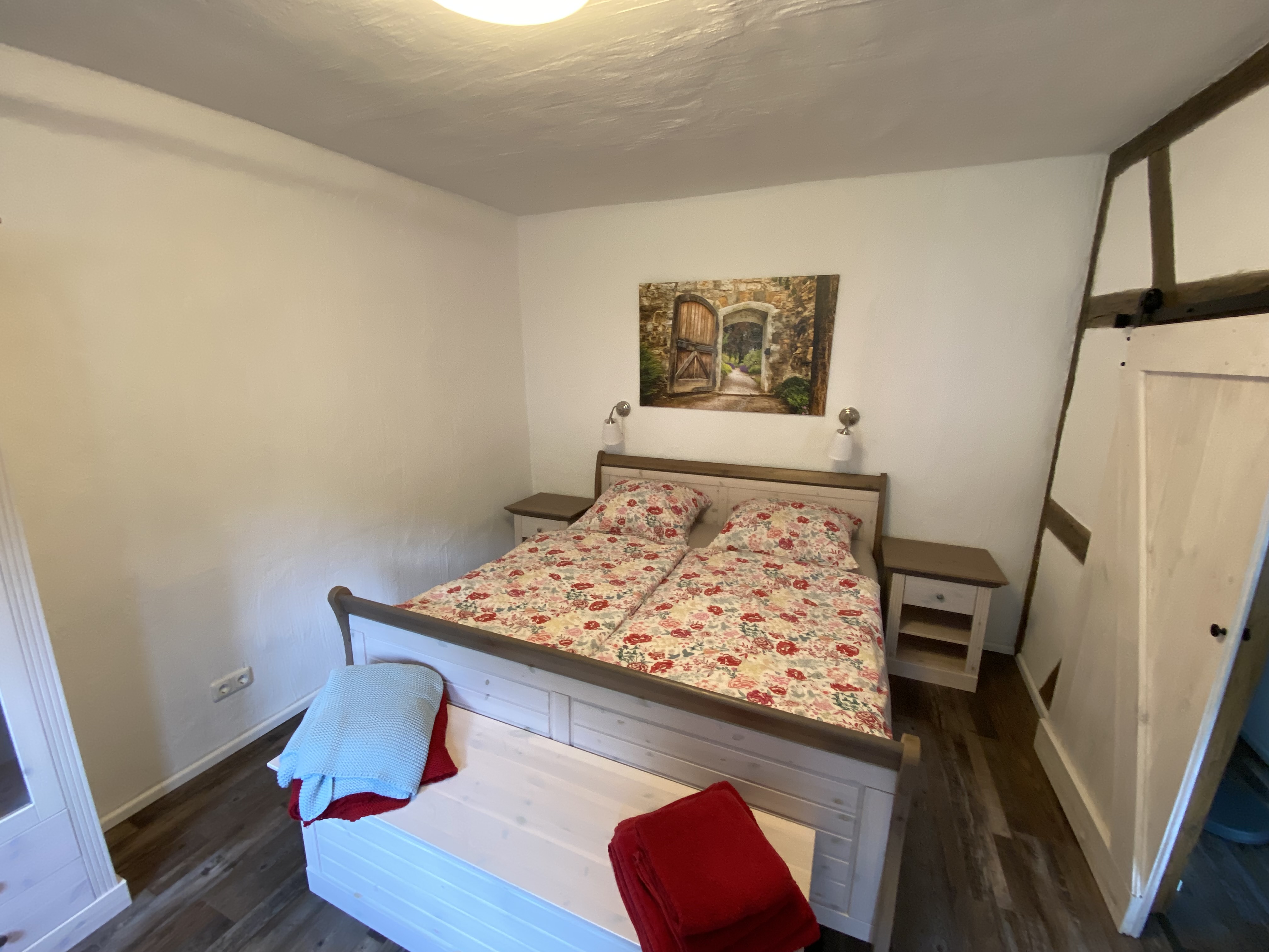 Schlafzimmer mit Doppelbett unter historischen Holzbalken